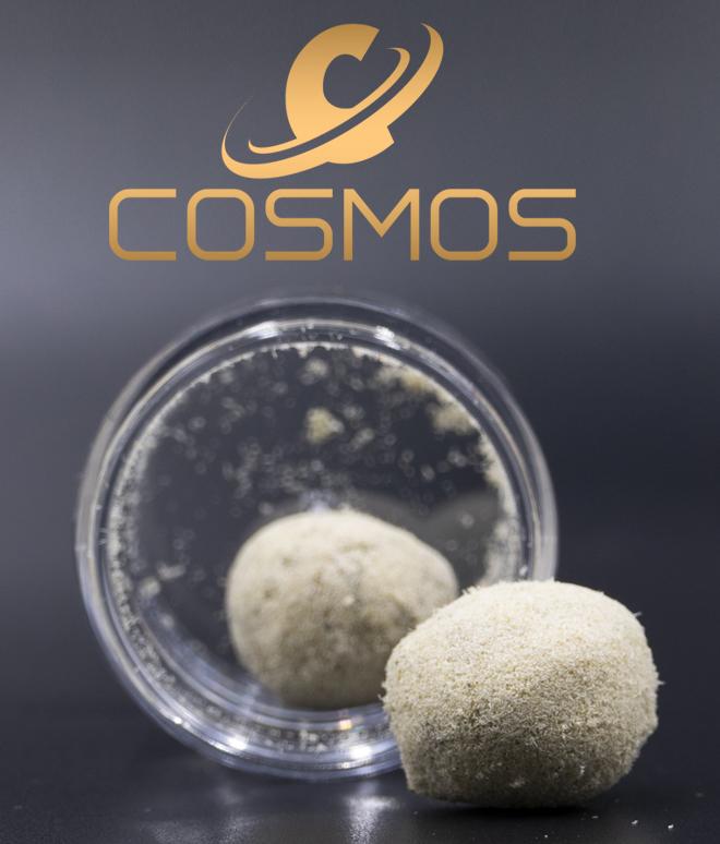 Close-up of Cosmos cannabis product in a clear jar, featuring a powdery, spherical concentrate.
